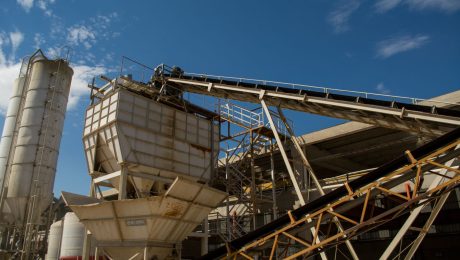 ga-greenbelt-1058143 Cement plant with storage silos and conveyor lines — industrial green belt context